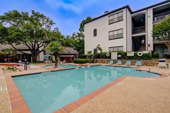 A swimming pool surrounded by a brick border and chairs.